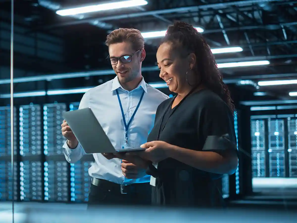 A pair of cybersecurity experts sharing a computer screen in a server room